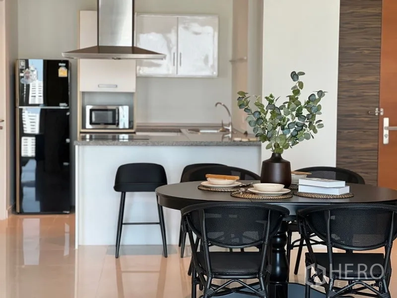 Condominium for rent in Watthana, Bangkok - Kitchen and dining detail featuring island counter, range hood and black dining chairs.