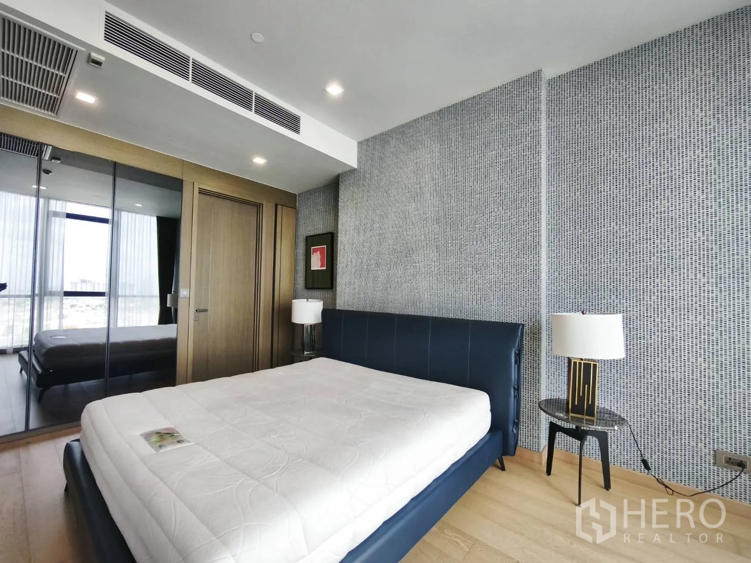 Condominium for rent in Watthana, Bangkok - Bright bedroom with upholstered bed, mirrored wardrobe, and bedside lamps.