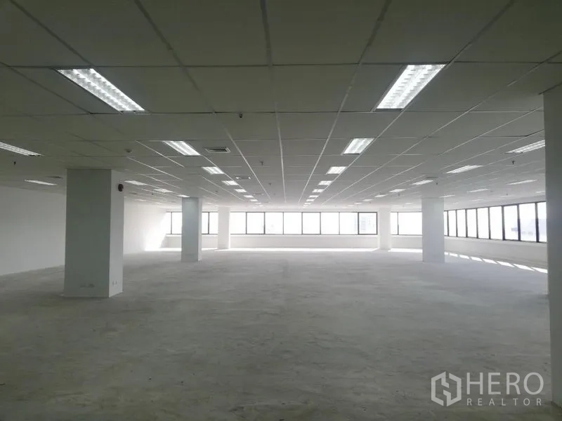 Office Space for rent in Watthana, Bangkok - Spacious bare‑shell office space with fluorescent lighting and panoramic windows for flexible layouts.