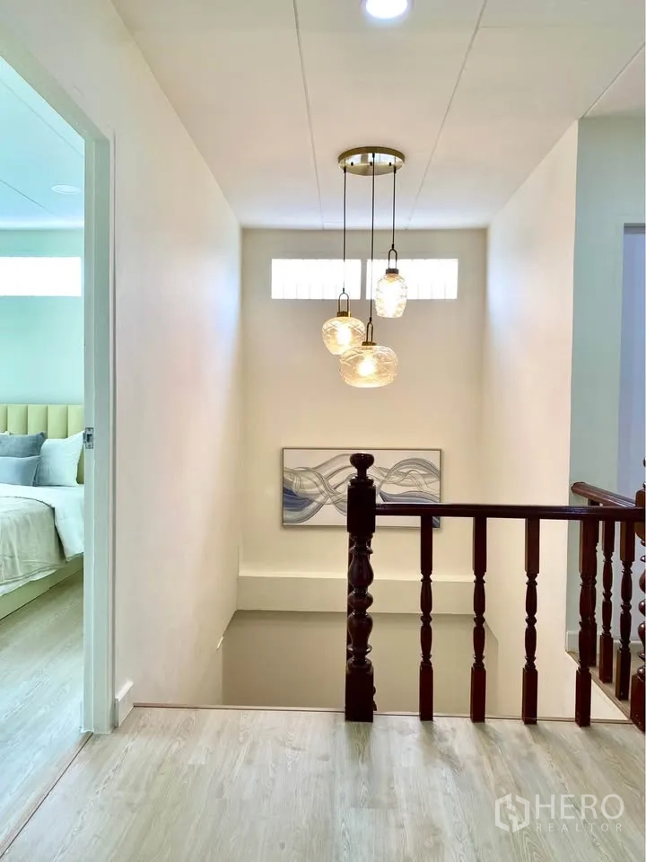 独栋房屋 for rent in Huai Khwang, Bangkok - 楼梯平台设吊灯、装饰画与木质栏杆。