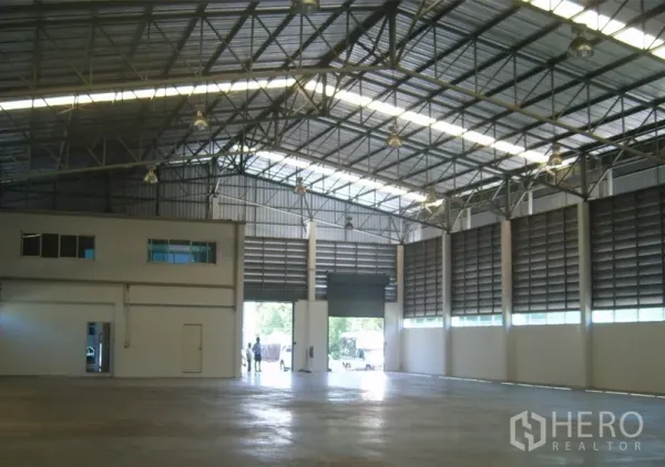 คลังสินค้า ให้เช่าในSamut Prakan - พื้นที่ภายในโกดังโปร่งเพดานสูง โครงเหล็ก ไฟส่องสว่าง และประตูม้วนขนาดใหญ่