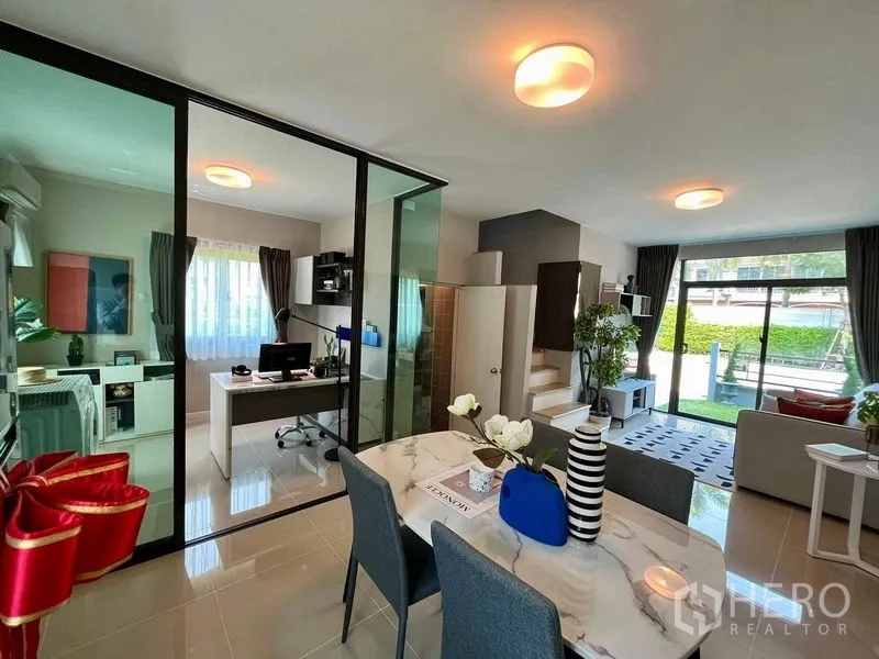 Townhouse for sale in Sai Mai, Bangkok - Dining zone beside a glass office, staircase, and sliding doors to the patio.