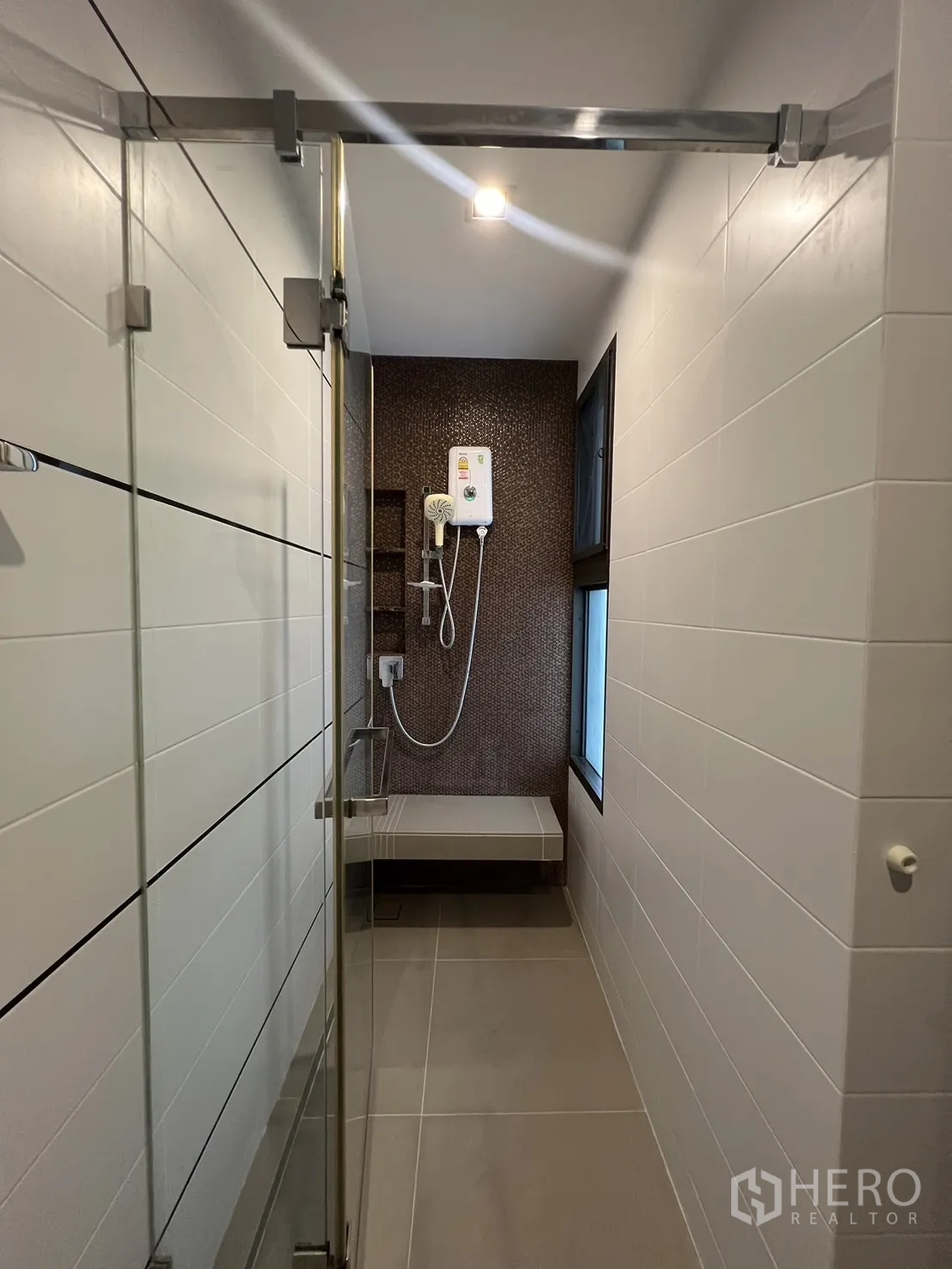 联排别墅 出租在Lat Phrao, Bangkok - 狹長淋浴間，玻璃門、瓷磚牆與電熱淋浴器。