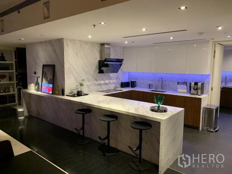公寓 出售在Sathon, Bangkok - 现代大理石厨房，长吧台与吧椅，橱柜下蓝色灯带。