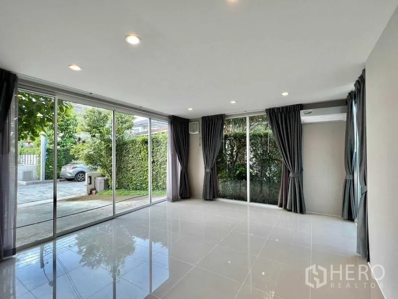 บ้าน ขายในBang Sao Thong, Samut Prakan - ห้องอเนกประสงค์กระจกบานเลื่อน เปิดออกสู่สวนและลานจอดรถ พร้อมแนวรั้วไม้พุ่ม