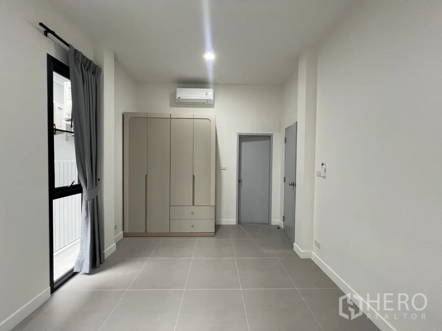 Detached House for rent in Saphan Sung, Bangkok - Spacious room with tiled floors, wardrobe, and air conditioner by a window.
