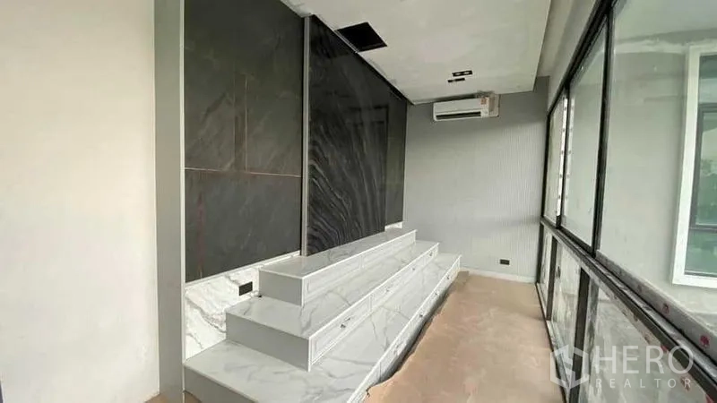 บ้าน ขายในMueang Nonthaburi, Nonthaburi - ชั้นวางทีวีหินอ่อนและผนังหินสีดำข้างหน้าต่างบานใหญ่พร้อมเครื่องปรับอากาศ