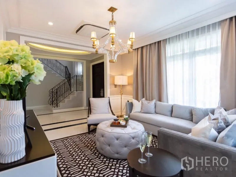 บ้าน ให้เช่าในMueang Samut Prakan, Samut Prakan - ห้องนั่งเล่นอบอุ่น โซฟาเข้ามุม โคมระย้า และมุมมองไปยังโถงบันได