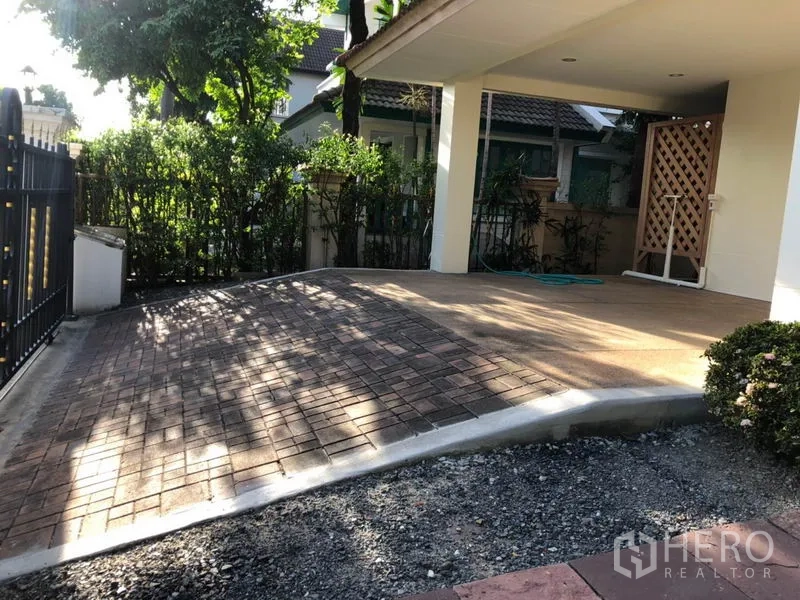 Detached House for rent in Saphan Sung, Bangkok - Covered carport and paved driveway inside a fenced yard with mature hedges.