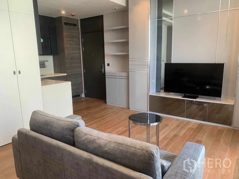 คอนโด ให้เช่าในPathum Wan, Bangkok - พื้นที่นั่งเล่นแบบเปิด โซฟา ตู้ทีวีบิวท์อิน และที่เก็บของ เชื่อมต่อกับครัวในคอนโดกรุงเทพฯ