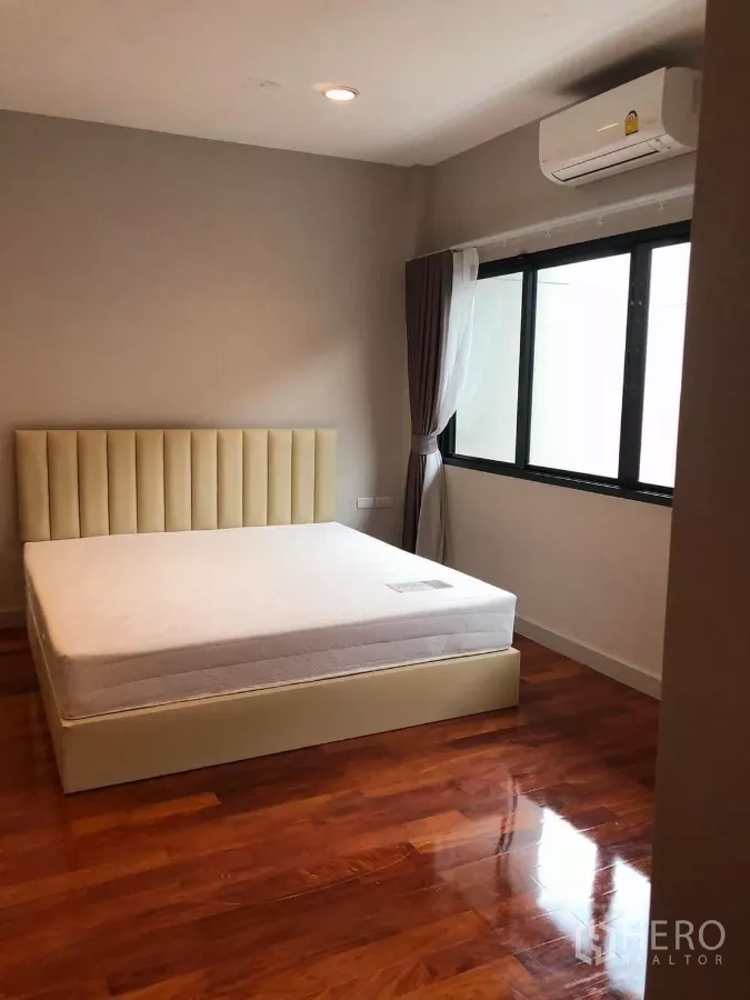 Detached House for rent in Bang Khae, Bangkok - Cozy bedroom with large window, air conditioning and polished wooden floor.