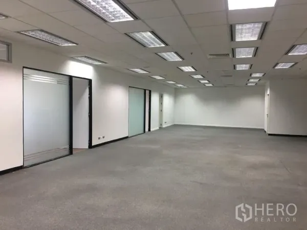 办公空间 出租在Chatuchak, Bangkok - 开放式办公区，吊顶格栅灯、白墙与多扇玻璃门。