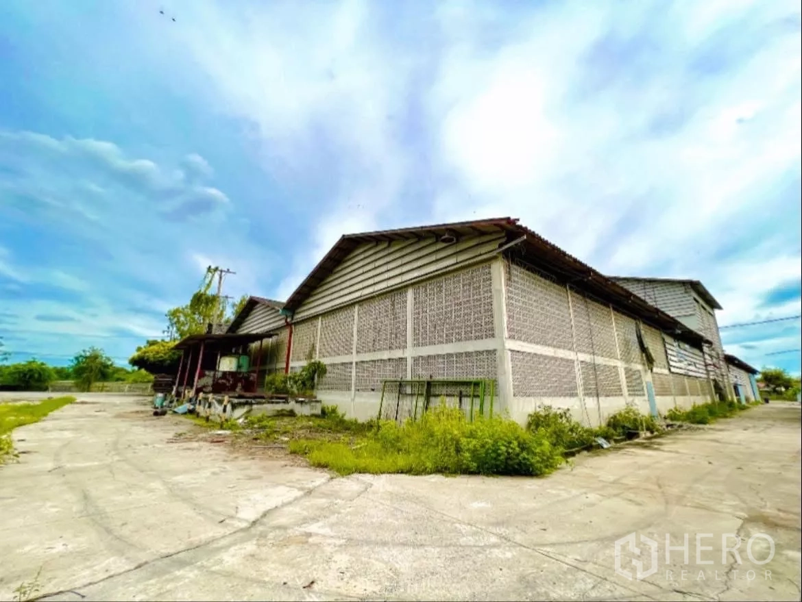 工厂 出租在Sai Noi, Nonthaburi - 工厂外角视图，通风砖墙体，侧边服务车道。