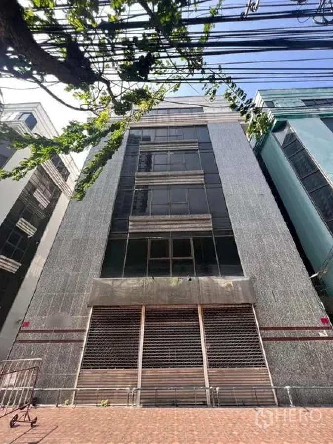 Shophouse for rent in Khlong San, Bangkok - Multi-storey shophouse exterior with granite-style facade and roller shutters.
