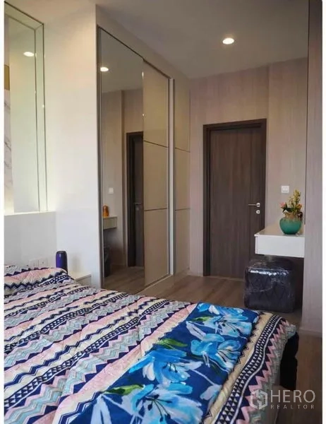 Condominium for rent in Huai Khwang, Bangkok - Cozy bedroom with built-in mirrored wardrobe and small dressing table.