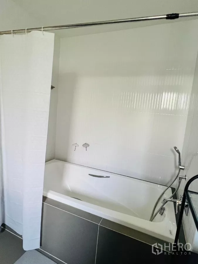 บ้าน ให้เช่าในSaphan Sung, Bangkok - ห้องน้ำพร้อมอ่างอาบน้ำสีขาว ม่านกั้น และฝักบัวมือถือ.