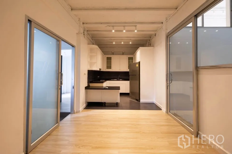 联排别墅 出租在Khlong Toei, Bangkok - 用餐区面向现代厨房，两侧为滑动玻璃门分隔。