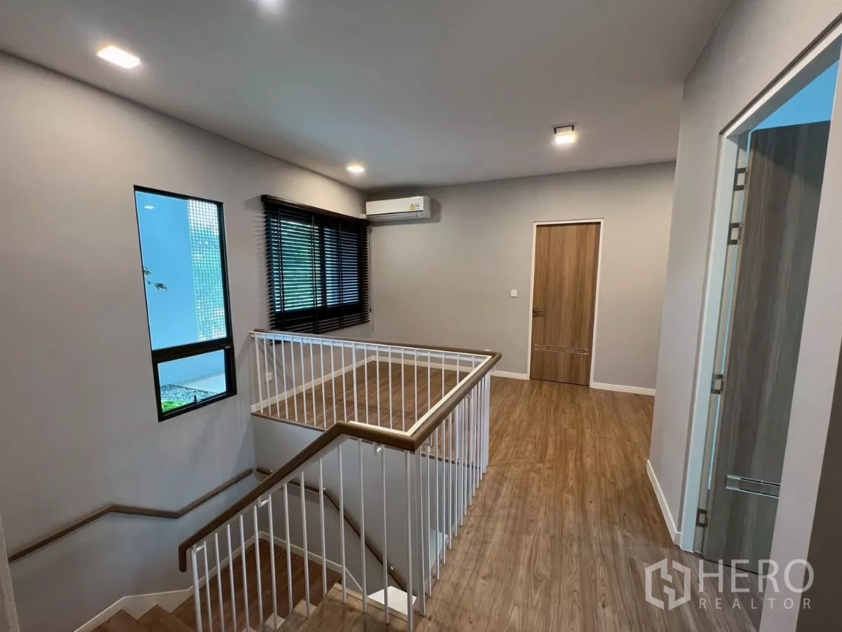 Detached House for rent in Samut Prakan - Stair hall and upper landing with wooden floors and white balustrade.