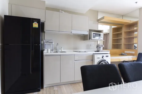 公寓 出租在Khlong Toei, Bangkok - 现代橱柜厨房，配黑色冰箱、微波炉、电磁炉与洗衣机。