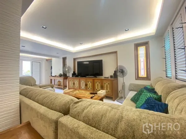 Detached House for sale in Khlong Toei, Bangkok - Bright living room with L-shaped sofa, TV console, and cove lighting.