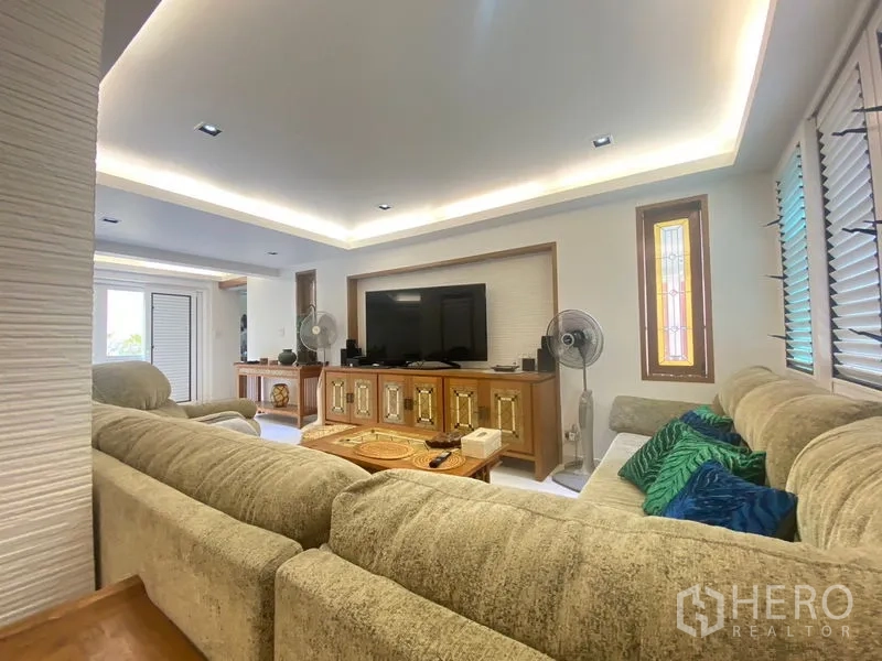 Detached House for sale in Khlong Toei, Bangkok - Bright living room with L-shaped sofa, TV console, and cove lighting.