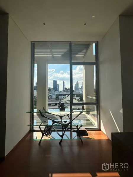 Condominium for rent or sale in Sathon, Bangkok - Compact study nook with glass desk and chair facing a balcony and skyline view.