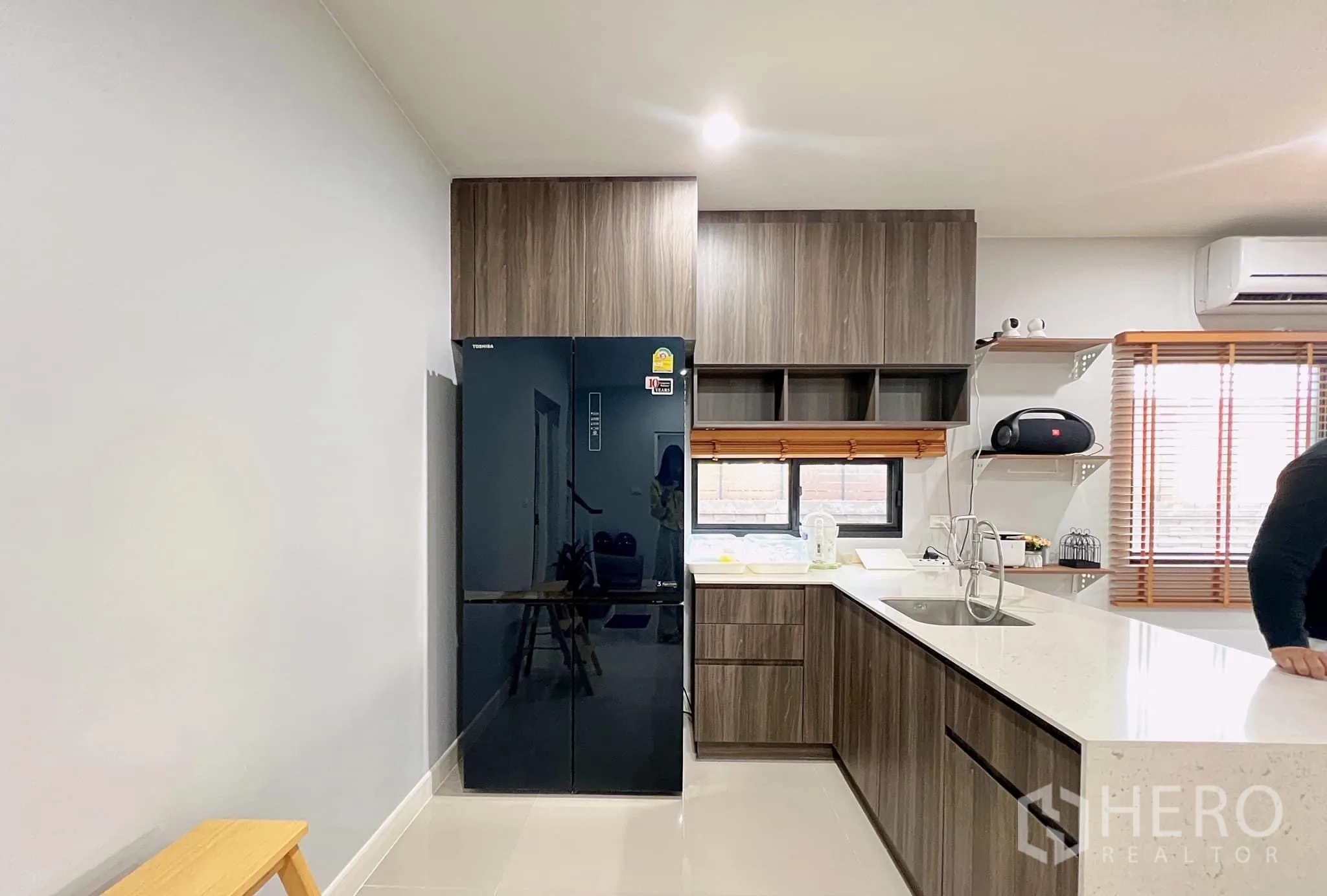 บ้าน ให้เช่าหรือขายในLam Luk Ka, Pathum Thani - ครัวแพนทรีรูปตัวแอล ตู้ไม้สีเข้ม ท็อปหินควอตซ์ และตู้เย็นสีดำ