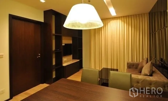 คอนโด ให้เช่าในKhlong Toei, Bangkok - มุมมองจากโต๊ะอาหารไปยังห้องนั่งเล่น มีชั้นบิลต์อิน โคมไฟแขวน และผ้าม่านทึบ