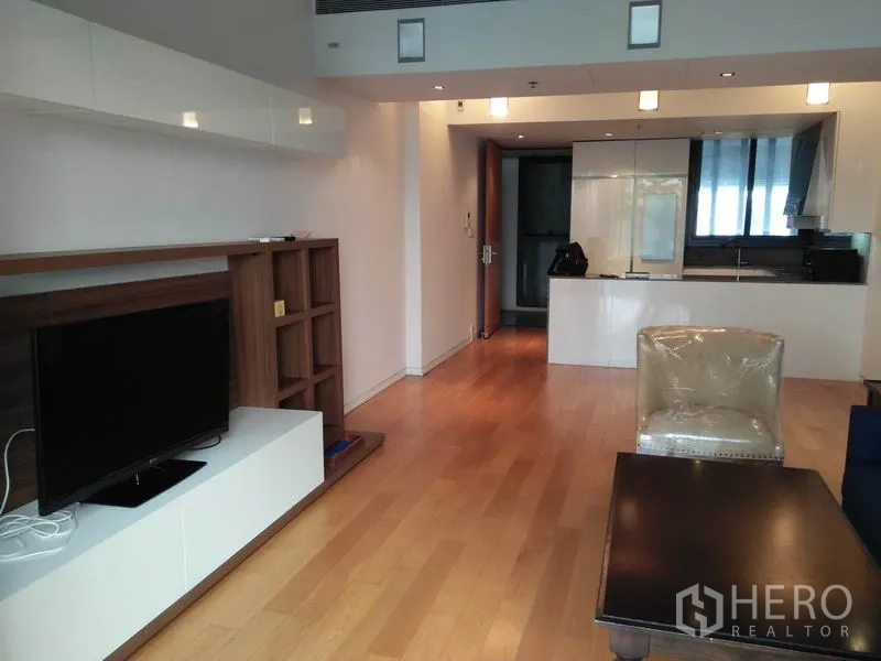 Condominium for rent in Sathon, Bangkok - Living room with TV console, shelving and view toward the kitchen in a Bangkok condominium.