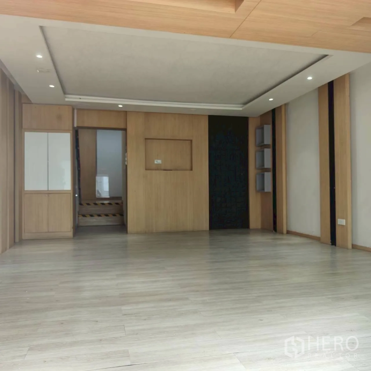 Home Office for rent in Watthana, Bangkok - Open-plan room with light wood floors, feature wall, and ceiling spotlights.