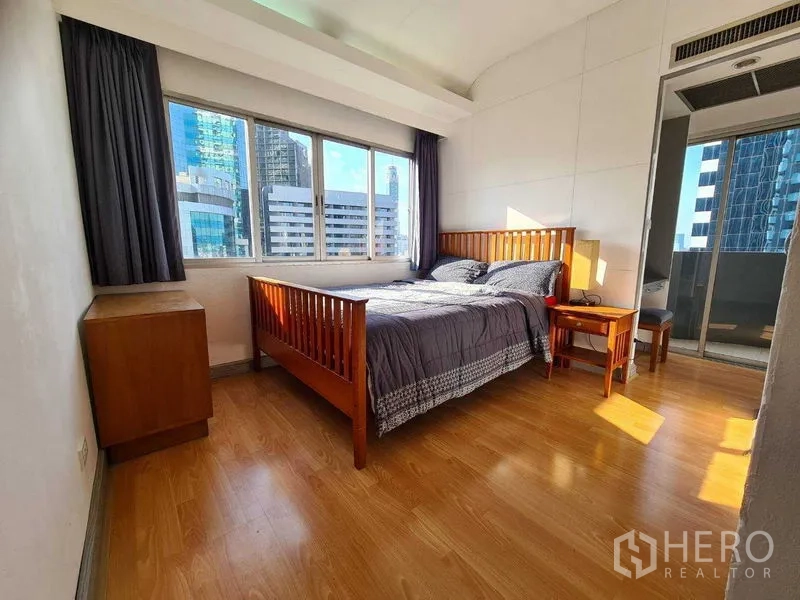 Condominium for rent in Ratchathewi, Bangkok - Master bedroom with big windows, wooden bed and balcony access.