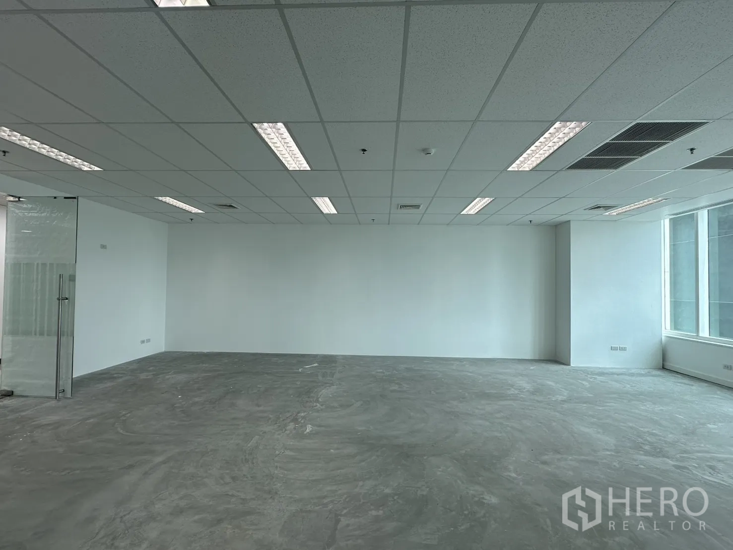 ออฟฟิศ for rent in Watthana, Bangkok - พื้นที่สำนักงานกว้าง เห็นประตูกระจกทางเข้า เพดานทีบาร์ และพื้นคอนกรีต.