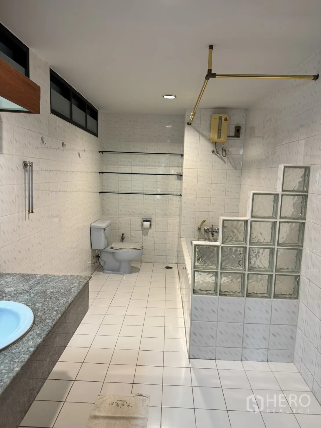 โฮมออฟฟิศ for rent in Watthana, Bangkok - ห้องน้ำกระเบื้องสีขาวพร้อมอ่างอาบน้ำ โถสุขภัณฑ์ และผนังกั้นบล็อกแก้ว