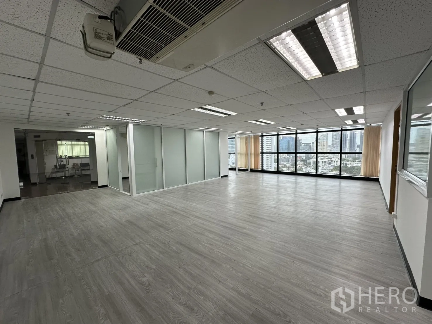 สำนักงาน ให้เช่าในWatthana, Bangkok - ภายในสำนักงานสว่าง พื้นลายไม้ ไฟฝังฝ้า ผนังกั้นกระจก พร้อมมุมมองสกายไลน์ย่านวัฒนา