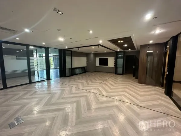 Office Space for rent - Spacious reception or work area with herringbone flooring, ceiling spotlights and glass-partitioned rooms.