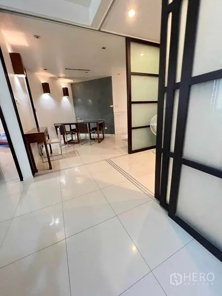 Condominium for rent in Ratchathewi, Bangkok - Dining area with table and chairs, wall sconces, and sliding partition.
