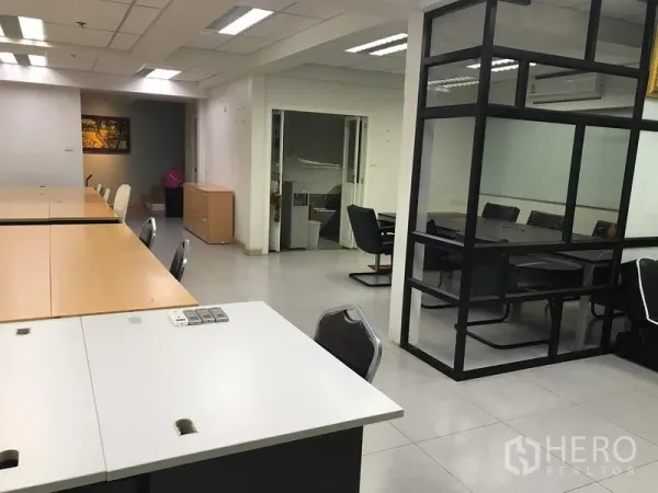 Office Space for rent in Khlong Toei, Bangkok - Open-plan office area with shared workstations and a glass-walled meeting room under bright ceiling lights.