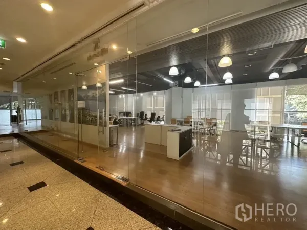 办公空间 出租在Pathum Wan, Bangkok - 从走廊透过整面玻璃立面看到的开放式办公区。
