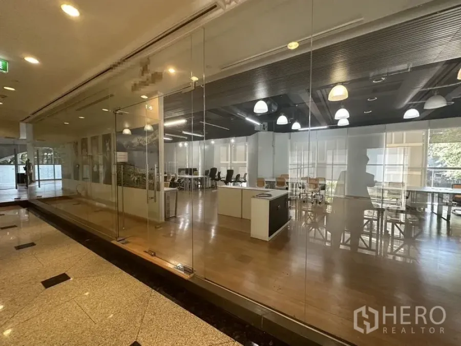 办公空间 出租在Pathum Wan, Bangkok - 从走廊透过整面玻璃立面看到的开放式办公区。