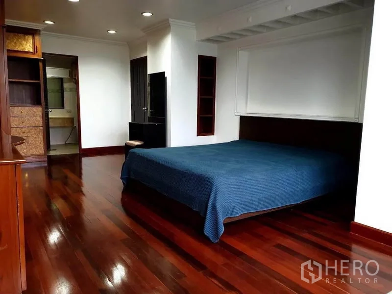 公寓 出租或出售在Watthana, Bangkok - 卧室配特大床、内置收纳与通往卫浴的入口，木地板。