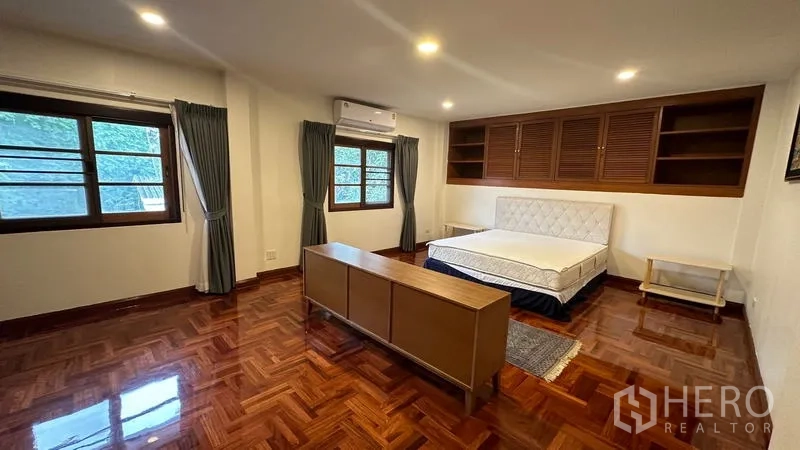 独立式住宅 出租在Watthana, Bangkok - 主卧宽敞，木地板、内置柜与多扇窗。