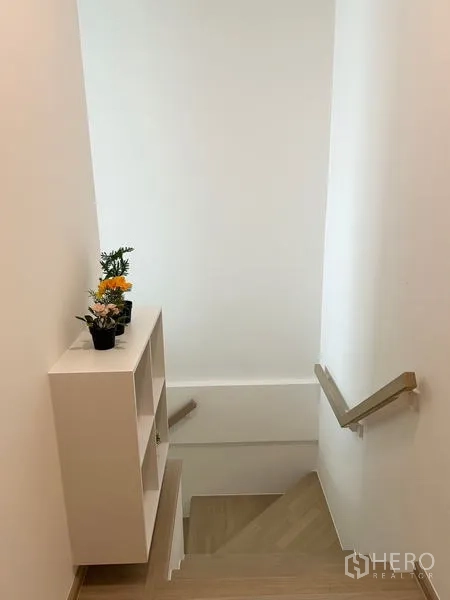 ทาวน์เฮาส์ ให้เช่า - บันไดไม้ ราวจับ และชั้นวางตกแต่งพร้อมต้นไม้กระถาง.