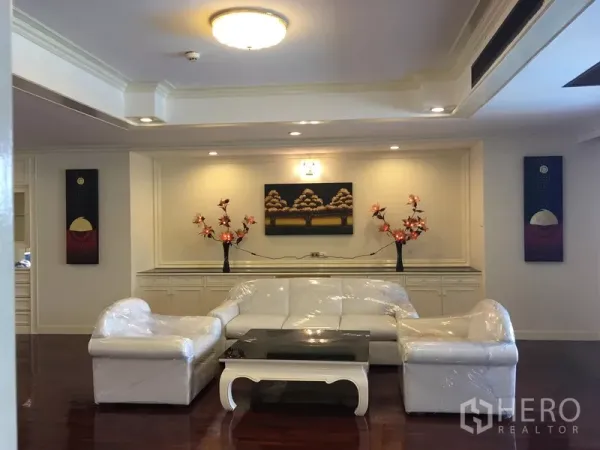 Condominium for rent in Watthana, Bangkok - Bright living room with white sofa set, wall art and polished wood floors.