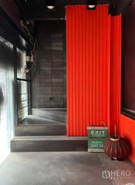 零售空间 出租在Khlong Toei, Bangkok - 入口小厅，红色装饰墙与黑砖背景，台阶式动线。