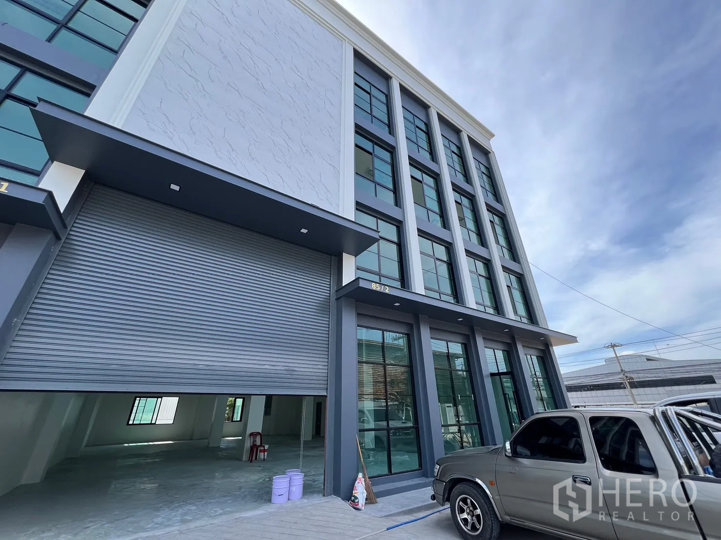 货栈 出租在Samut Prakan - 临街仓库外观，超大卷闸门，多层玻璃办公室与停车区。