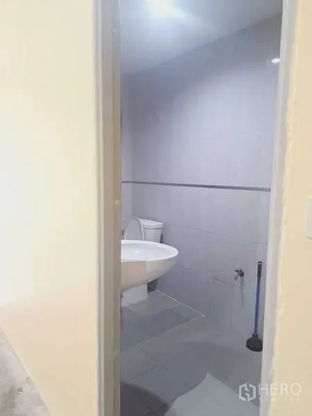 货栈 出租在Mueang Samut Prakan, Samut Prakan - 浅灰色瓷砖卫生间，配坐便与壁挂式洗手盆及顶灯。