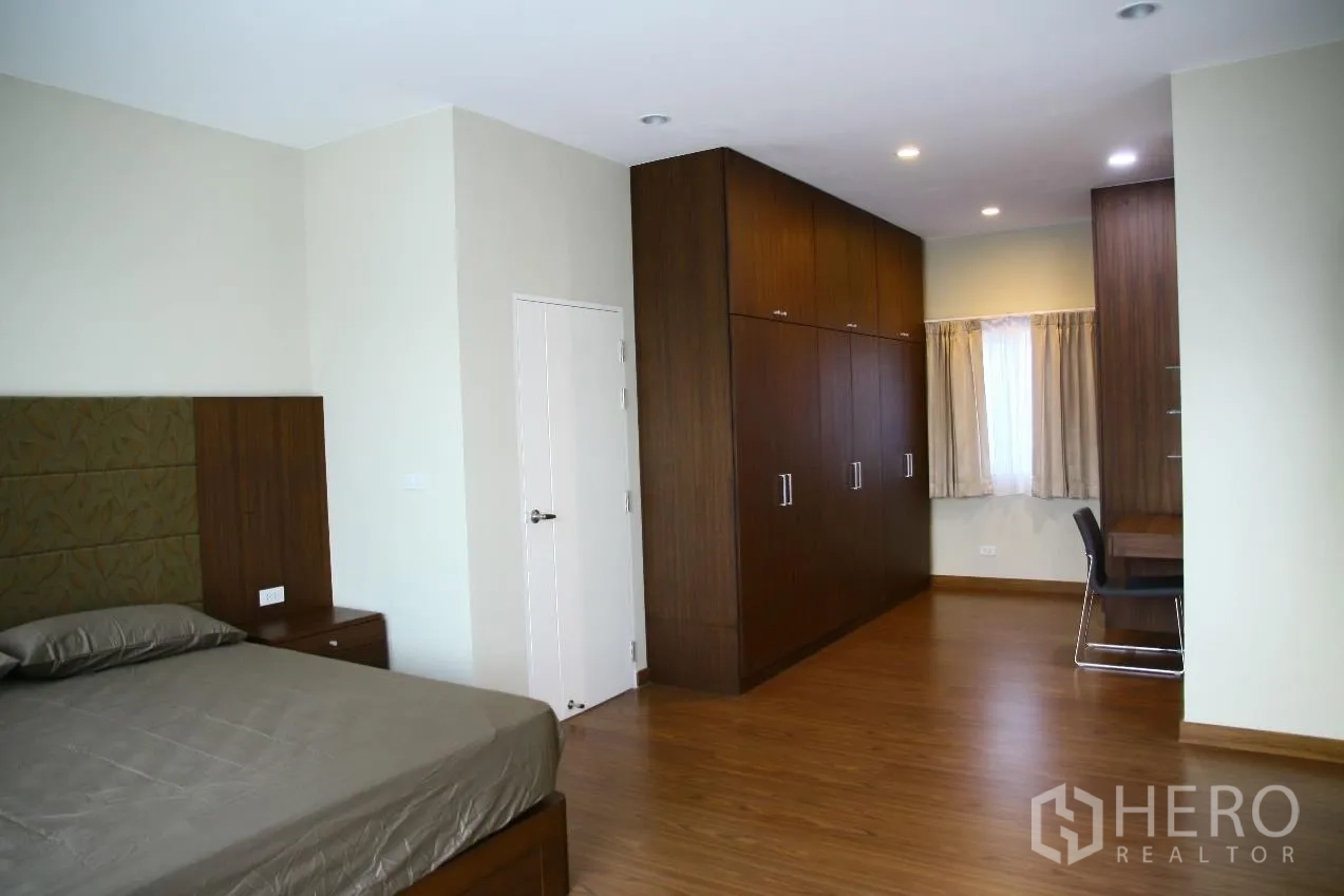 Detached House for rent or sale in Bang Na, Bangkok - Master suite with long built-in wardrobes, study desk and recessed lighting over wood floors.