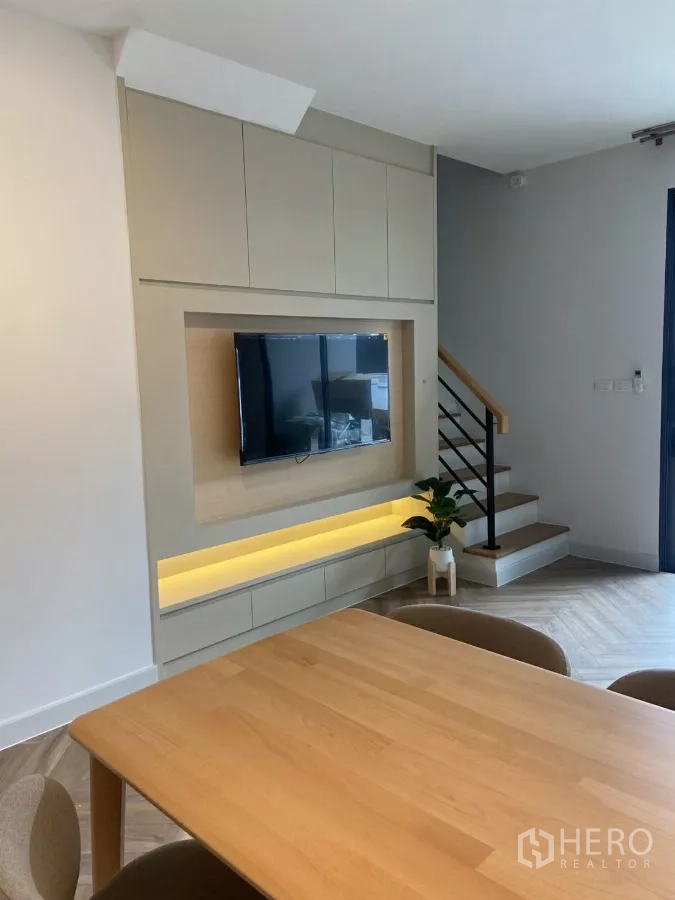Townhouse for rent in Bang Phli, Samut Prakan - TV feature wall with storage, LED lighting and staircase beside the living area.