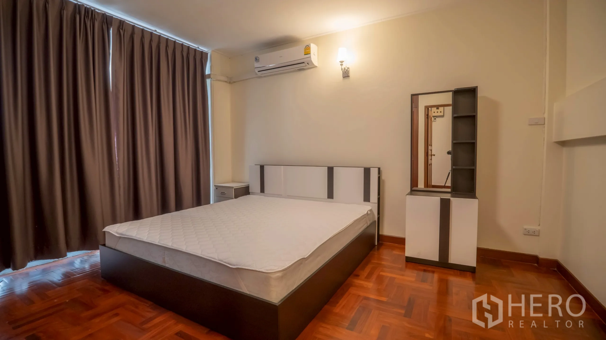 Townhouse for rent in Khlong Toei, Bangkok - Bedroom with bed, air conditioner, dressing table and dark curtains.