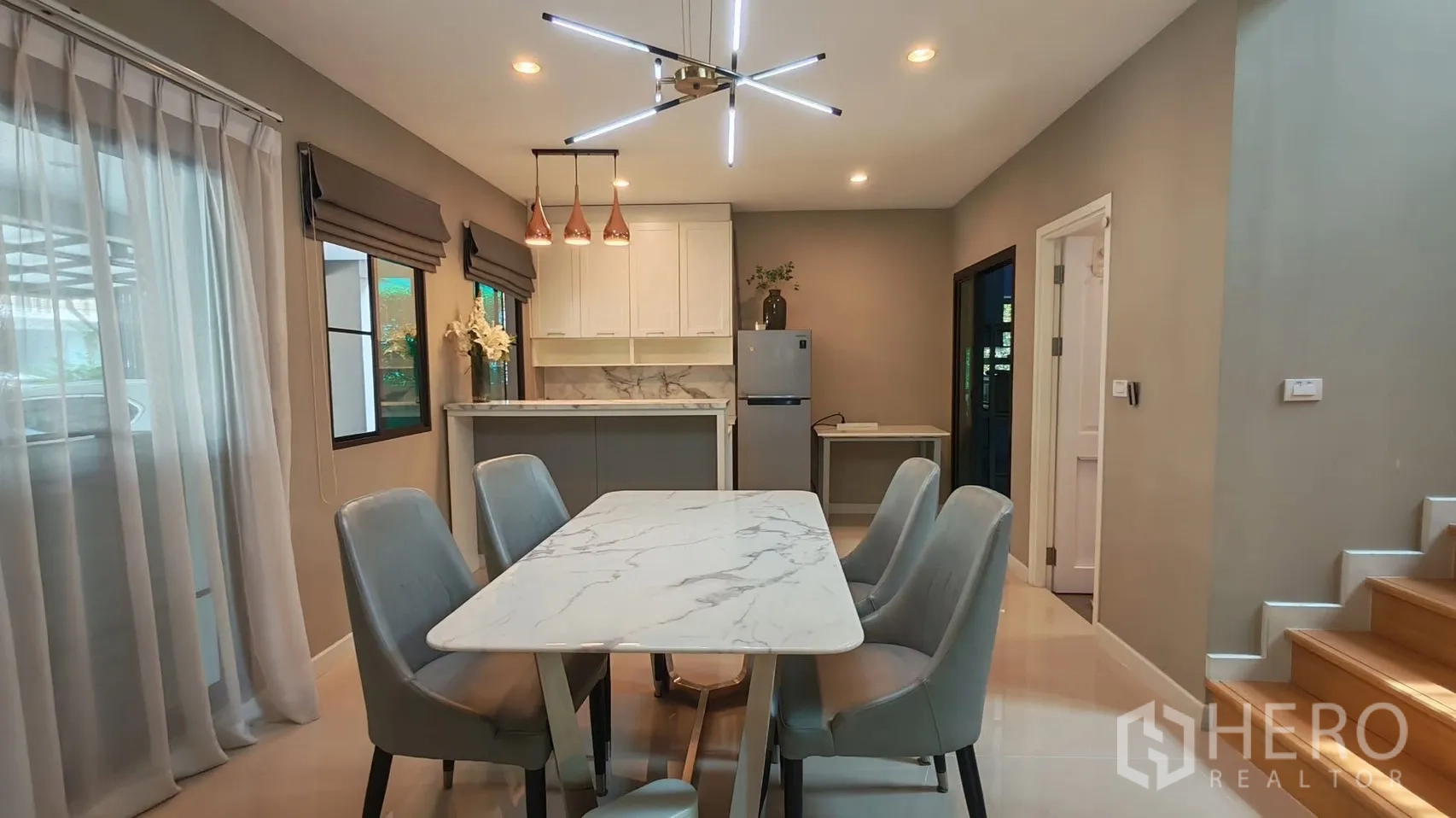 独栋房屋 for rent or sale in Bang Phli, Samut Prakan - 餐厅设大理石餐桌、吊灯与吧台，旁边是楼梯。